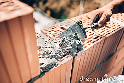 Worker using trowel and tools for building exterior walls with bricks and mortar Stock Photo