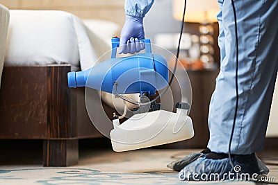 Worker in virus protective suit disinfecting room of corona virus with the sprayer Stock Photo