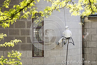 A worker wearing a protective gear cleaning a stone facade Stock Photo