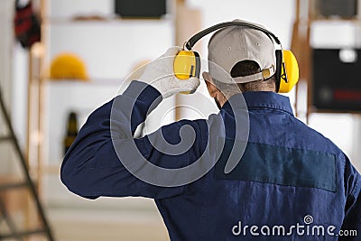 Worker wearing safety headphones indoors, back view. Hearing protection device Stock Photo