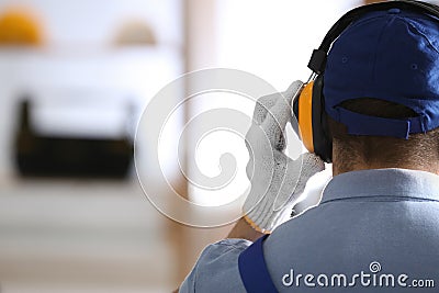 Worker wearing safety headphones indoors, back view with space for text. Hearing protection device Stock Photo