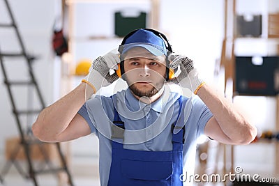 Worker wearing safety headphones indoors. Hearing protection device Stock Photo