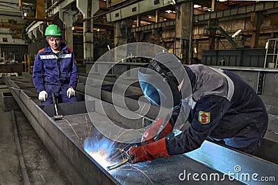 Worker welder manually weld steel sheets using gas torch, MIG. Editorial Stock Photo