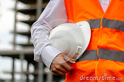 Worker with white safety helmet and orange vest. Construction and industrial site workers concept Stock Photo