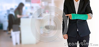 worker woman accident on arm with green arm cast on blurred business office working space background Stock Photo