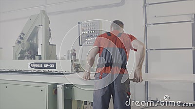 Worker working at sawing machine in production. Action. Worker controls process of cutting wooden board on automated Editorial Stock Photo