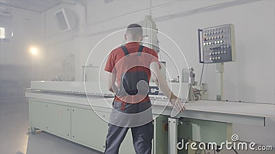 Worker working at sawing machine in production. Action. Worker controls process of cutting wooden board on automated Editorial Stock Photo