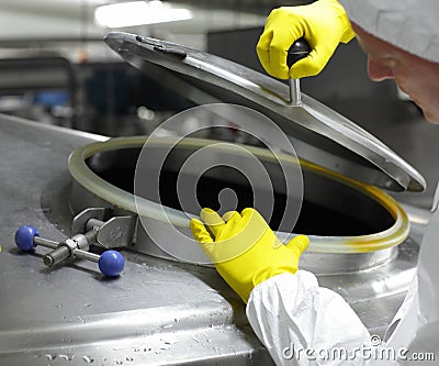 Worker in yellow gloves opening industrial process tank Stock Photo