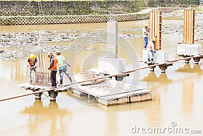 Workers building bridge foundation across lake Stock Photo