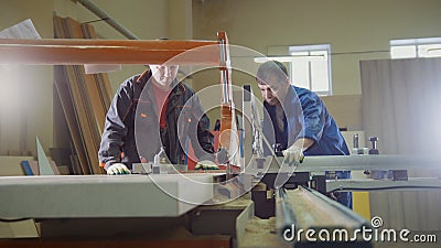 Workers carpenters are cutting wood board on electric saw at furniture factory Stock Photo