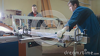 Workers carpenters are cutting wooden detail on electric saw at furniture factory Stock Photo