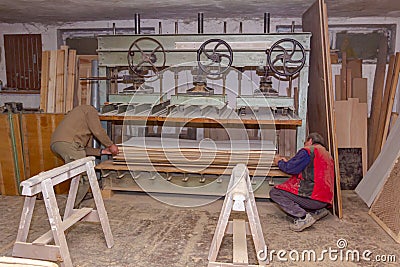 Workers in carpentry placed glued wooden profiles in the large clamp machine for pressing Stock Photo