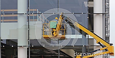 Workers on a cherry picker. They are finishing the glass facade of a building under renovation Stock Photo
