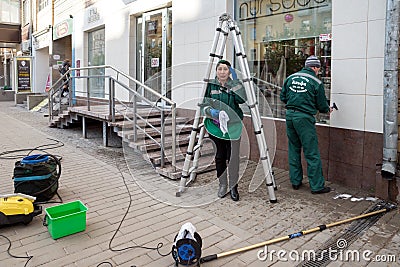 Workers of the cleaning company are cleaning the facade and engaged in washing windowsafter repairing an office. Editorial Stock Photo