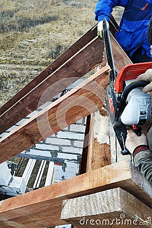 Workers cut the rafters on the roof of the chainsaw house Stock Photo