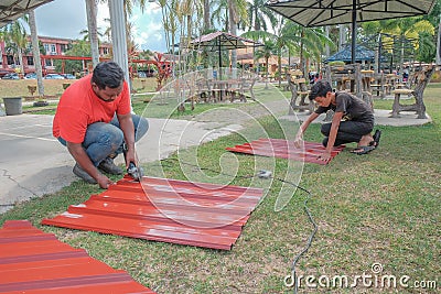 The workers is cutting a metal gazebo roof using a grinder Editorial Stock Photo