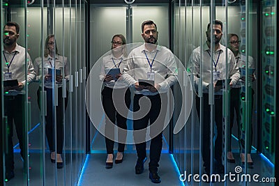 Workers in a data center walking between rows of server racks Stock Photo