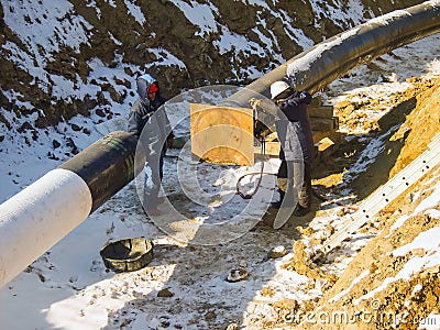 The workers engaged in the construction of the pipeline. Welders build the pipeline. Installation work in the construction and ins Editorial Stock Photo