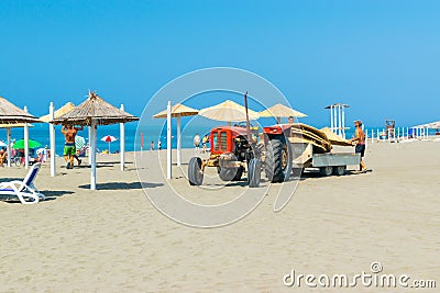 Workers equip the sand Long Beach (Velika plaza) with umbrellas brought on a tractor. Ulcinj, Montenegro. Adriatic Sea Editorial Stock Photo