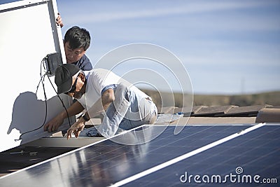 Workers Fixing Solar Panel On Roof Top Stock Photo