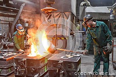 workers in a foundry casting a metal workpiece - safety at work and teamwork Stock Photo