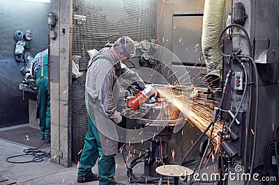 Workers in a foundry grind castings with a grinding machine - He Stock Photo