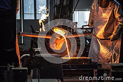 Workers in a foundry safely casting a metal workpiece Stock Photo