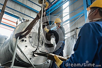 Workers handling equipment for lifting industrial boilers Stock Photo