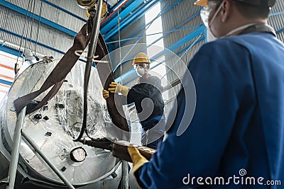 Workers handling equipment for lifting industrial boilers Stock Photo