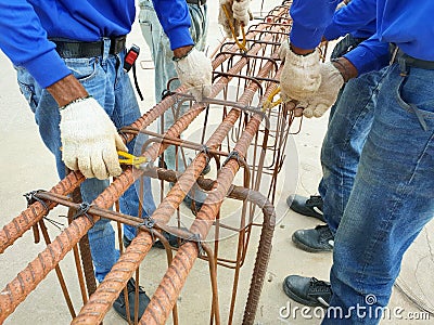 Workers hands using steel wire for securing steel bars with wire rod for reinforcement. Stock Photo