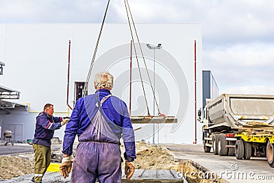 Workers are helping on ground, mobile crane is carry cement slab Editorial Stock Photo