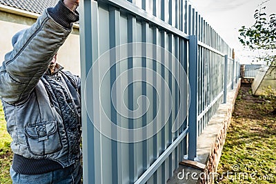 Workers install of gray fence from metal profile Stock Photo