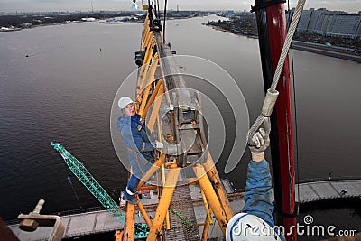 Workers installers fixed working construction boom hoisting tower crane Editorial Stock Photo