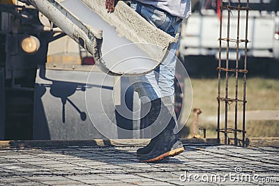 Workers Legs were pouring concrete in construction site. Poor Labor wear boot and mix Cement on floor Stock Photo