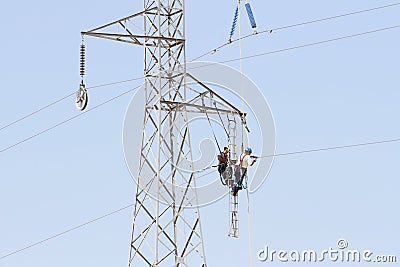 Workers over a high tension tower making reparations. Editorial Stock Photo