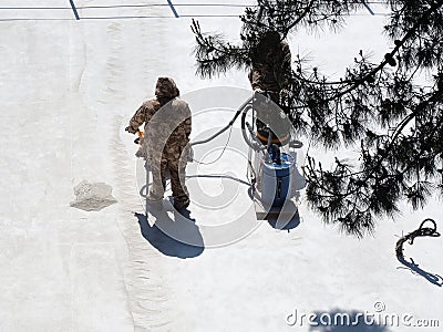 Workers in overalls remove construction dust from a concrete pavement in a sunlit area with an industrial vacuum cleaner Stock Photo