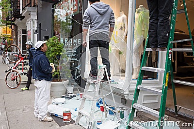 Workers paint the front of ready-made clothing store Editorial Stock Photo