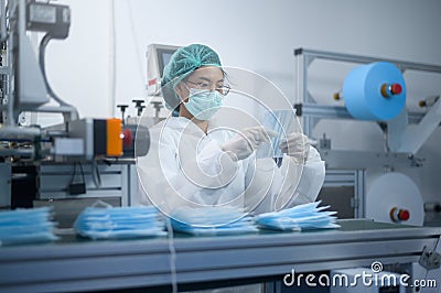 Worker producing surgical mask in modern factory, Covid-19 protection and medical concept Stock Photo