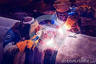 Workers with protective masks welding bore pile metal casing at a construction site. Stock Photo