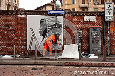 Workers are putting up posters showcasing the Moncler collection of 2023 on the walls, Milan Editorial Stock Photo