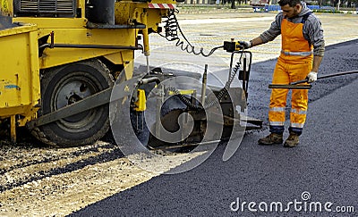 Workers regulate tracked paver laying asphalt Stock Photo