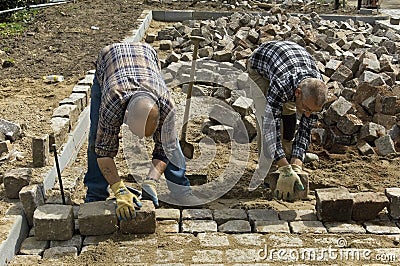 Workers: road builders laying cobblestones Editorial Stock Photo