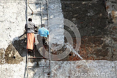 Workers stand on ladder and paint a big wall Editorial Stock Photo