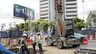 Workers stand near an excavator Editorial Stock Photo