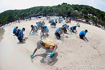 Workers and volunteers are shoveling sand with crude oil contaminated on the beach in a large plastic bag Editorial Stock Photo