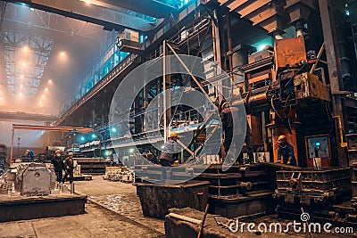 Workers work with molds for smelting iron at steel mill in factory workshop. Foundry, heavy industry, steelworks Editorial Stock Photo