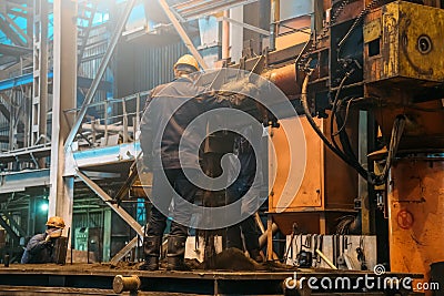 Workers work with molds for smelting iron at steel mill in factory workshop. Foundry, heavy industry, steelworks Editorial Stock Photo