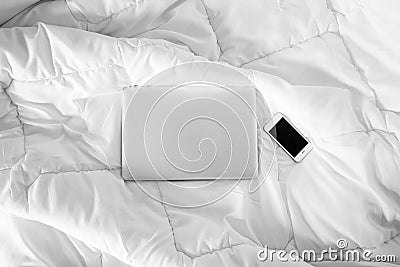 Working in bed , laptop and smartphone on white bed, morning light Stock Photo