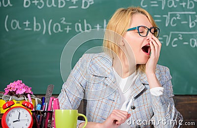 Working conditions for teachers. Work far beyond the actual school day. Woman tired teacher sit table classroom Stock Photo