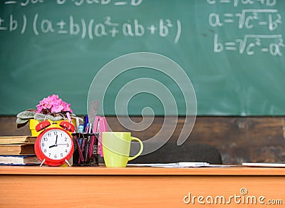 Working conditions which prospective teachers must consider. Table with school supplies alarm clock books and mug Stock Photo